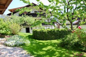 un giardino con prato verde e cespugli e un edificio di Ferienwohnung Fanese a Flintsbach am Inn