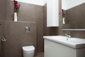 een badkamer met een wastafel, een toilet en bloemen bij Luxury apartments Vila Carissa in Malinska