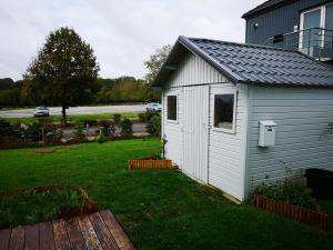a small white shed sitting in a yard at Bungalow du Lac in Froid-Chapelle