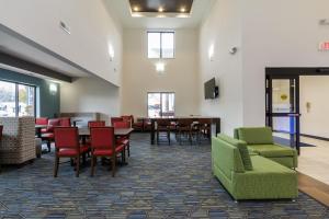 Holiday Inn Express & Suites - South Bend - Notre Dame Univ. في ساوث بند: غرفة انتظار مع كراسي وطاولات وتلفزيون