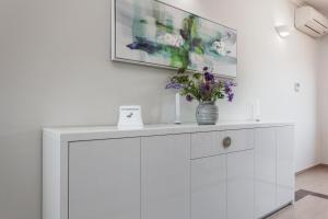 a white cabinet with a vase of flowers on it at Luxury apartments Vila Carissa in Malinska