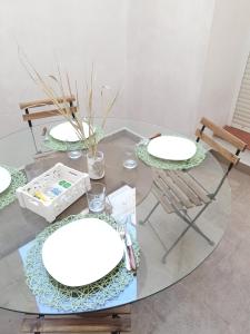 a glass table with two white plates and a chair at Apartamento San Juan 1 in Murcia