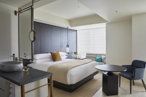 a bedroom with a bed and a table and a chair at Kimpton Shinjuku Tokyo, an IHG Hotel in Tokyo