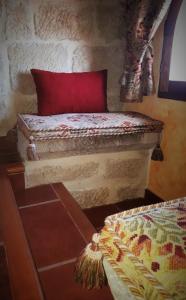 a bed with a red pillow in a room at Casa Rural Medieval Torre Fuerte S.XIII in Baños de Rioja