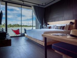 sypialnia z dużym łóżkiem i dużym oknem w obiekcie Cross River Kwai w mieście Kanchanaburi