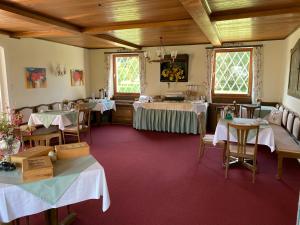 un comedor con mesas, sillas y ventanas en Hotel - Garni Stabauer, en Mondsee