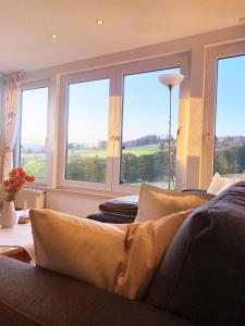 a living room with a couch and windows with a view at Haus Panorama Sankt Andreasberg in Sankt Andreasberg