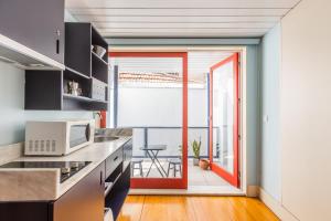 a kitchen with a red door leading to a balcony at Victoria Studios @ Clérigos in Porto