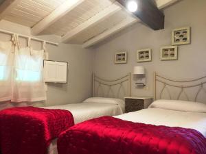 a bedroom with two beds with red blankets and a window at Agroturismo Ibarra in Amorebieta-Etxano
