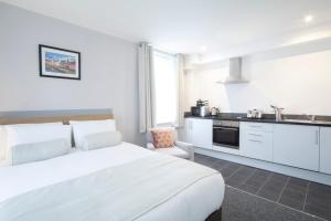 a white bedroom with a white bed and a kitchen at Wellington Apartments in Norwich