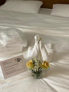 Una cama blanca con toallas y flores. en Hotel Goldene Rose, en Ebersbach an der Fils