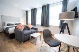 uma sala de estar com uma cama, um sofá e uma mesa em Wellington Apartments em Norwich