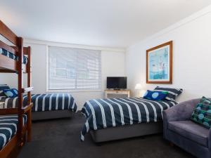 a bedroom with two beds and a couch at Corlette Waterfront 2 Waterfront Luxury WI FI Aircon Boat Parking in Corlette
