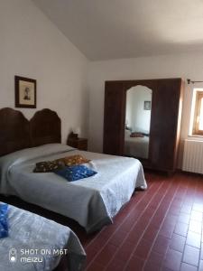 ピアンカスタニャーイオにあるPodere del Piccini con piscina in val d Orcia Toscanaのベッドが2つと鏡があるホテルの部屋