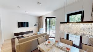 een woonkamer met een eettafel en een kroonluchter bij White Pearl Apartment 3.04 in Timmendorfer Strand
