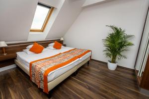 ein Schlafzimmer mit einem Bett mit orangefarbenen Kissen und einer Pflanze in der Unterkunft Vinosseum Bor- és Apartmanház in Sopron