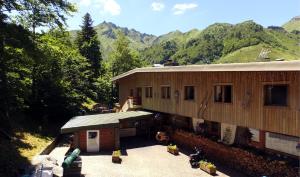 a large building with a porch and mountains in the background at Auberge de Jeunesse HI Le Mont-Dore in Le Mont-Dore