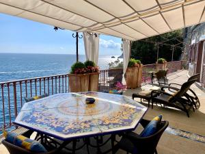 una mesa y sillas en un balcón con vistas al océano en Villa Le Baste, en Furore