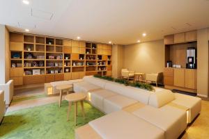 a library with a large couch and tables and shelves at JR Inn Sapporo Kita 2 Jo in Sapporo