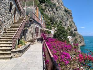 un grupo de escaleras y flores junto al océano en Villa Le Baste en Furore
