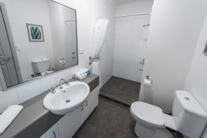 a white bathroom with a sink and a toilet at Cosy Corner Sea View Apartments in Albany +26 photos
