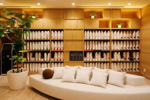 a room with a white couch in front of a wall of vases at JR Inn Sapporo Kita 2 Jo in Sapporo