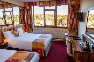 una camera d'albergo con due letti e una scrivania di West County Hotel a Chapelizod
