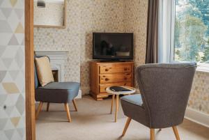 a living room with two chairs and a television at Three Wells B&B in Llandrindod Wells