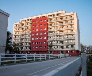 a red building with a white fence next to a road at Dream Arena Apartment in Bacău
