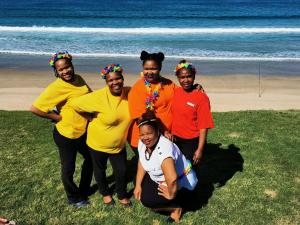 a group of people posing for a picture at the beach at Bay Lodge on the Beach in Mossel Bay
