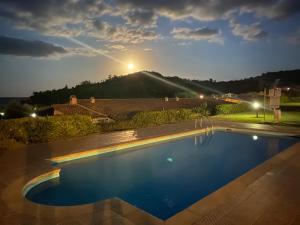 a swimming pool at night with a mountain in the background at Abba Urci in Tertenìa
