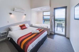 a bedroom with a bed and a bathroom with a tub at Cosy Corner Sea View Apartments in Albany