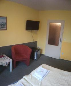 a hotel room with a bed and a chair and a television at Penzion Měšťanský Dům in Svoboda nad Úpou