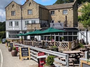 ein Restaurant mit Tischen und Sonnenschirmen vor einem Gebäude in der Unterkunft Millstone Country Inn in Hathersage