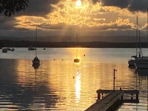 um pôr-do-sol sobre um corpo de água com barcos em Starfish Cottage em Cams Wharf