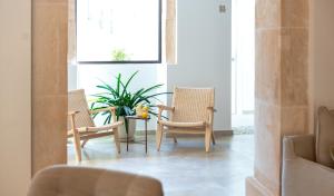 アリアーニにあるYnaira hotel & Spaの椅子3脚、テーブル1脚、植物1本が備わる部屋