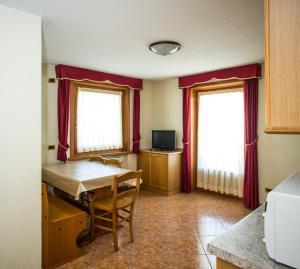 a dining room with a table and two windows at Appartamenti Alba in Livigno