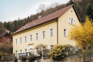 ein gelbes Haus mit einem Zaun davor in der Unterkunft Ferienwohnungen Königstein in Königstein an der Elbe