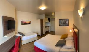 a hotel room with two beds and a flat screen tv at Villa Val Senart 1ere Avenue in Quincy-sous-Sénart