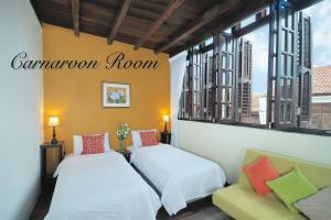 two beds in a room with windows at Carnarvon House in George Town
