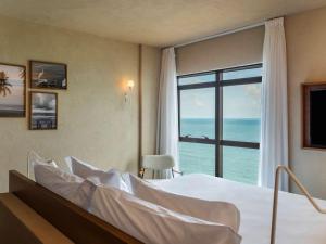 Grand Mercure Recife Boa Viagem في ريسيفي: غرفة نوم مع سرير وإطلالة على المحيط