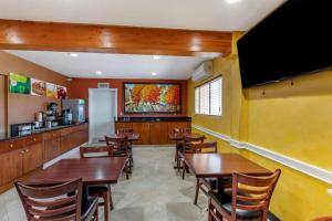 un restaurante con mesas y sillas de madera y una pantalla grande en Quality Inn & Suites Westminster Seal Beach en Westminster