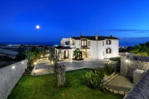 Une grande maison blanche avec la lune dans le ciel dans l'établissement Villa Domus Petraianca, à Marina di Ragusa