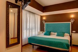 Schlafzimmer mit einem Bett mit einem grünen Kopfteil und einem Spiegel in der Unterkunft Hostel Costa Gijon in Gijón
