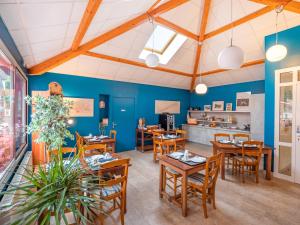 comedor con paredes azules y mesas y sillas de madera en La Vieille Auberge du Lac, en Saint-Agnan