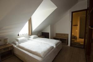 a bedroom with a white bed and a large window at Jégverem Fogadó in Sopron