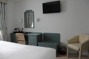 een slaapkamer met een bed, een bureau en een televisie bij Centennial Hotel in Cambridge