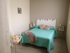 a bedroom with a bed with a green comforter and a chair at Casa Rural Vereda - Fábrica de Cerveza in Ledigos