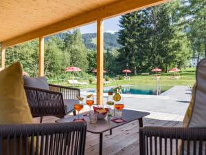 un patio con mesa, sillas y piscina en Harmony Hotel Sonnschein, en Niederau