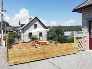 a wooden deck with a picnic table in front of a house at Gîte de Granit Noir in Besse-et-Saint-Anastaise